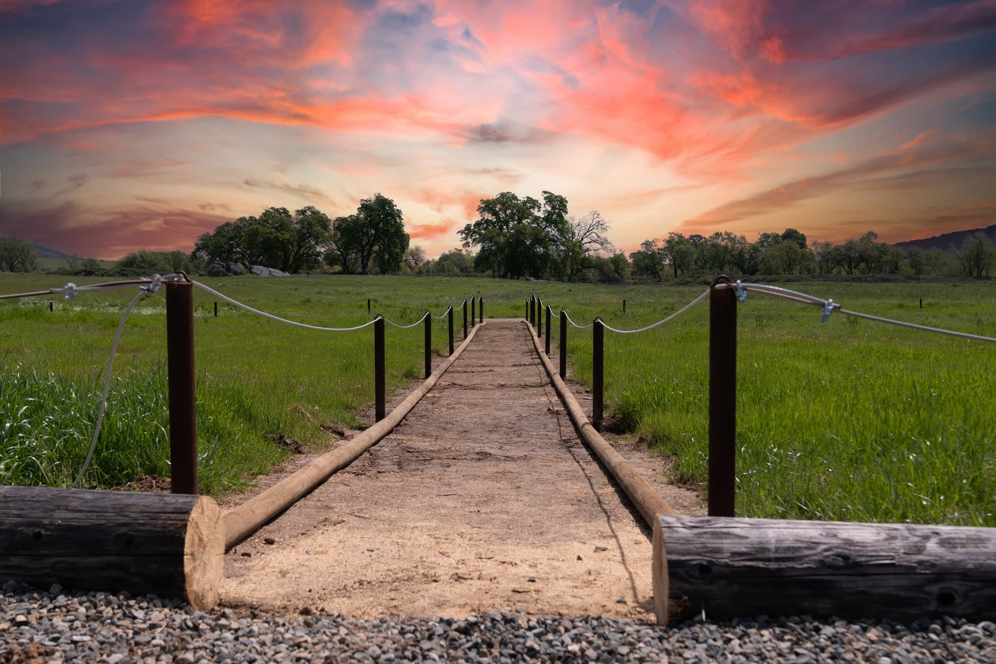 Rope-lined natural burial path leading into a golden meadow at sunset