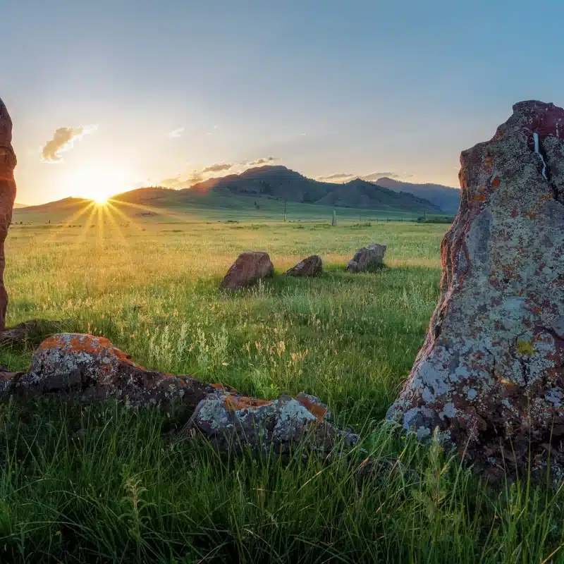 Sunset over grassy field with standing stones and hills for Green Burial Services in San Mateo County, California