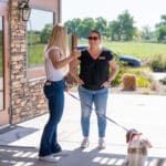 Two women talking outside with a dog on a leash.