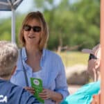 Woman discussing with seated men at outdoor event
