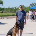 Man standing with German Shepherd in sunny park