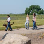 Three women walking dog on rural pathway
