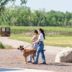 Three women walking a dog in sunny park