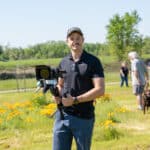 Man with camera filming outdoors in sunny field