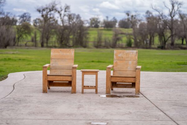 Two wooden chairs and table overlooking green field