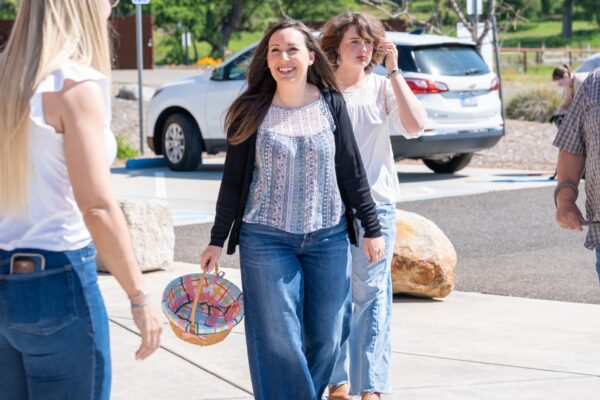 _A745241 Three women walking and smiling in sunny parking lot