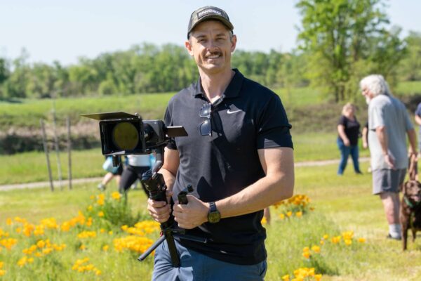 _A745333 Man filming outdoors with camera stabilizer, sunny day