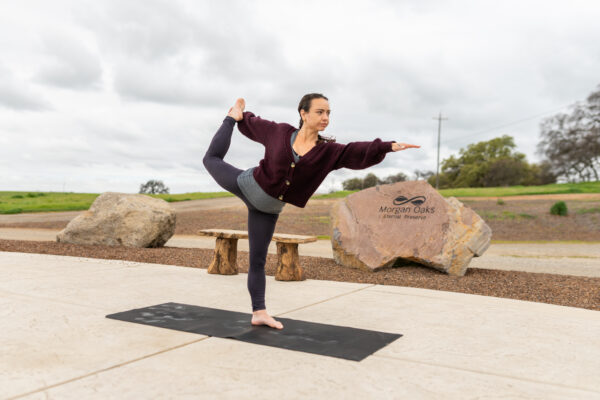 _A747853 Woman performing yoga in park near engraved rock